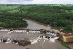 Foto aérea da Pequena Central Hidrelétrica Salto Morais, pertencente à Cemig. A usina fica no Rio Tijuco, que tem águas escuras e fica em meio a uma área verde.