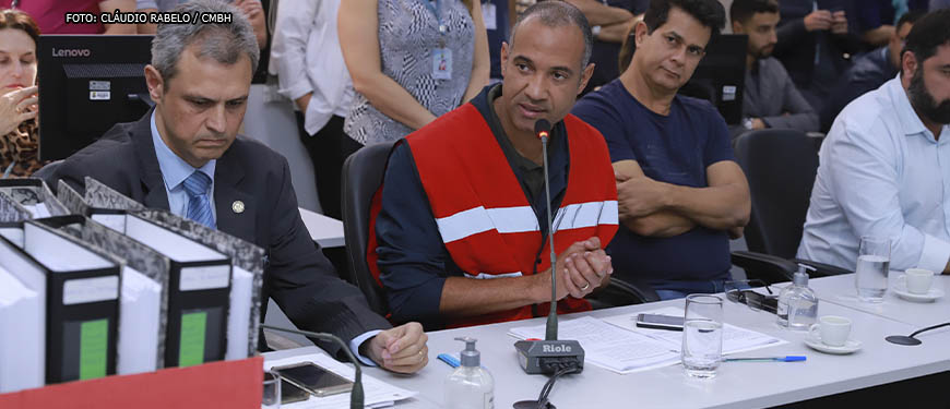 Wagner Ferreira, homem negro, grisalho, ele está vestido com um colete vermelho com faixas refletivas e fala ao microfone durante sessão da CPI da Lagoa da Pampulha. Conteúdo textual: OPINIÃO - JORNAL O TEMPO PUBLICA ARTIGO DE WAGNER FERREIRA SOBRE LAGOA DA PAMPULHA.