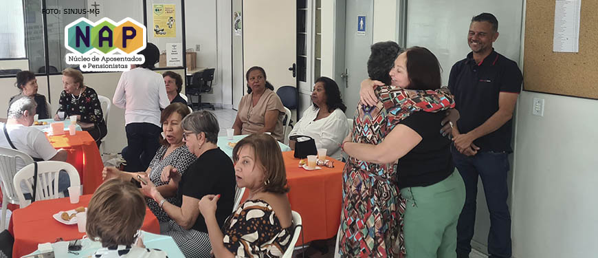 rupo de aposentados e pensionistas reunidos com Alex Aguiar, diretor de aposentados e pensionistas do SINJUS-MG, em reunião de reencontro do NAP (Núcleo de Aposentados e Pensionistas). As expressões faciais demonstram que o grupo está alegre e descontraído.