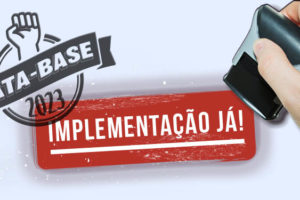 Foto montagem de uma imagem com fundo branco onde se vê uma mão de um homem de pele clara, segurando um carimbo, em cima do fundo branco se vê o escrito carimbado em vermelho "Implementação já!", no mesmo espaço o logo da Data-Base 2023, onde se vê um punho levantado.