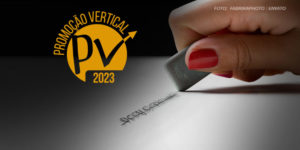 Na imagem há uma mão feminina com uma borracha, ela está apagando uma anotação riscada em um papel branco. No alto, em um fundo preto há um selo onde se lê Promoção Vertical 2023