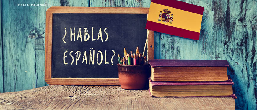 Imagem acessível: Imagem com livros, lápis de cor e quadro negro com os dizeres "¿Hablas español?"