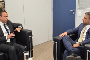 A imagem mostra dois homens de terno conversando sentados em poltronas pretas em um escritório. Sobre a mesa à frente, há pilhas de livros e copos de água. Na parte superior da imagem lê-se “Igualdade Racial”.