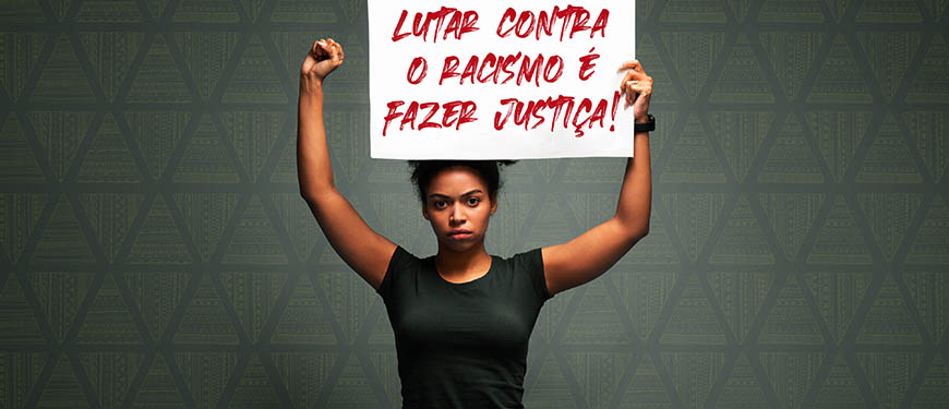 fundo cinza com destaque ao centro para um jovem negra, de cabelos crespos, usando camisa preta e segurando ao alto um cartaz com os dizeres: Lutar contra o racismo é fazer Justiça!