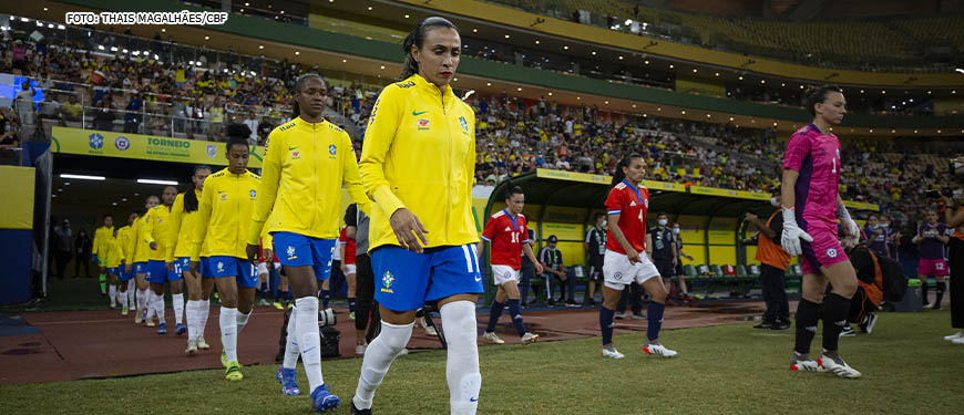 Seleção brasileira feminina de futebol entrando em campo, elas estão vestidas com o uniforme verde amarelo da CBF. Em destaque está a jogadora Marta. Conteúdo textual: COPA DO MUNDO FEMININA - SINJUS REQUER QUE TJ FLEXIBILIZE EXPEDIENTE NOS DIAS DE JOGOS.