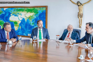 Mesa de reunião com o presidente Lula, estão presentes o presidente do Senado, Rodrigo Pacheco, e o presidente da ALMG, Tadeu Leite. Também estão na imagem os ministros Alexandre Silveira, Rui Costa e Fernando Haddad.