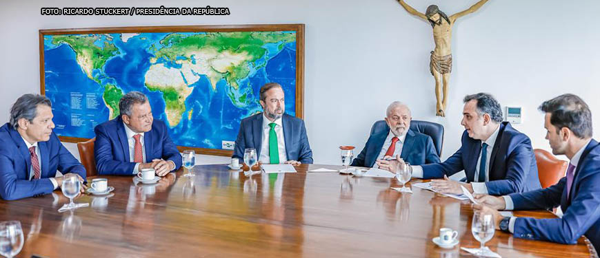 Mesa de reunião com o presidente Lula, estão presentes o presidente do Senado, Rodrigo Pacheco, e o presidente da ALMG, Tadeu Leite. Também estão na imagem os ministros Alexandre Silveira, Rui Costa e Fernando Haddad.