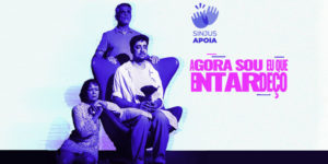 Imagem Acessível: Divulgação do espetáculo “Agora sou eu que entardeço”, em cartaz na Campanha de Popularização do Teatro e da Dança de Belo Horizonte. No canto superior direito Há um selo de duas mãos batendo palmas com o texto SINJUS APOIA. Em destaque, está a atriz Sidnéia Simões, filiada ao sindicato, ao lado de dois atores do elenco, a foto está em tons de roxo e azul. Conteúdo textual: Prestigie! Filiada ao SINJUS é destaque em espetáculo da campanha de teatro.