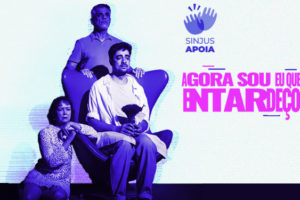 Imagem Acessível: Divulgação do espetáculo “Agora sou eu que entardeço”, em cartaz na Campanha de Popularização do Teatro e da Dança de Belo Horizonte. No canto superior direito Há um selo de duas mãos batendo palmas com o texto SINJUS APOIA. Em destaque, está a atriz Sidnéia Simões, filiada ao sindicato, ao lado de dois atores do elenco, a foto está em tons de roxo e azul. Conteúdo textual: Prestigie! Filiada ao SINJUS é destaque em espetáculo da campanha de teatro.