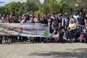 Grupo de pessoas ao ar livre, em clima descontraído com uma faixa do 31º Passeio Ecológico do SINJUS.