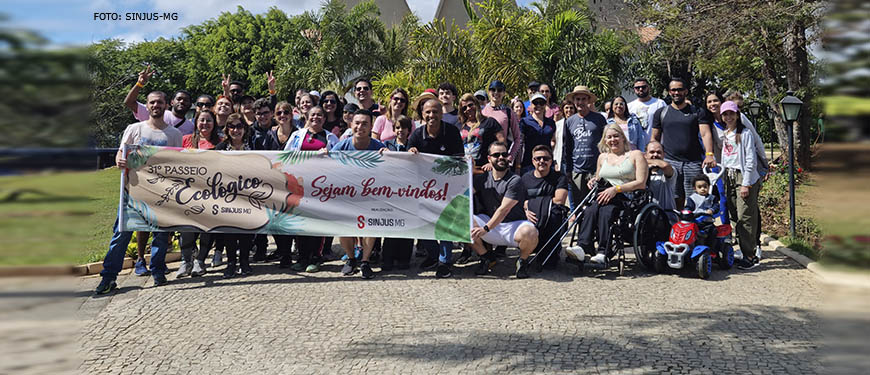 Grupo de pessoas ao ar livre, em clima descontraído com uma faixa do 31º Passeio Ecológico do SINJUS.