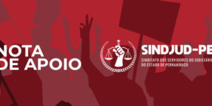 fundo texturizado com imagem vetorizada de uma multidão protestando com cartazes, em destaque está a silhueta de uma pessoa com um cartaz onde se lê "Nota de Apoio" e a logo do Sindjud-PE