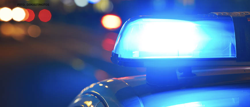 Imagem acessível: Foto noturna de uma viatura policial com foco no giroflex azul.