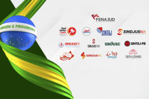 Card do SINJUS-MG sobre as Eleições 2026, com fundo em tons de branco, cinza e verde-escuro. Na parte superior, uma ilustração tridimensional mostra uma esfera azul com estrelas brancas e a faixa “Ordem e Progresso”, representando a bandeira do Brasil, envolvida por faixas verdes e amarelas. Na parte inferior, aparecem a logomarca da Fenajud e os símbolos de diversos sindicatos do Judiciário brasileiro que apoiam o manifesto, incluindo o SINJUS-MG. Conteúdo textual: Eleições 2026 - SINJUS se une à Fenajud e assina manifesto em defesa do serviço público.