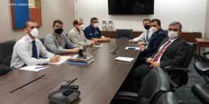 Sentados à mesa, de um lado, representantes do SINJUS, Serjusmig e Sindojus/MG, e, de outro lado, representantes do TJMG (sete homens brancos, de cabelos curtos, trajados socialmente usando máscaras respiratórias).
