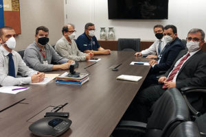 Sentados à mesa, de um lado, representantes do SINJUS, Serjusmig e Sindojus/MG, e, de outro lado, representantes do TJMG (sete homens brancos, de cabelos curtos, trajados socialmente usando máscaras respiratórias).