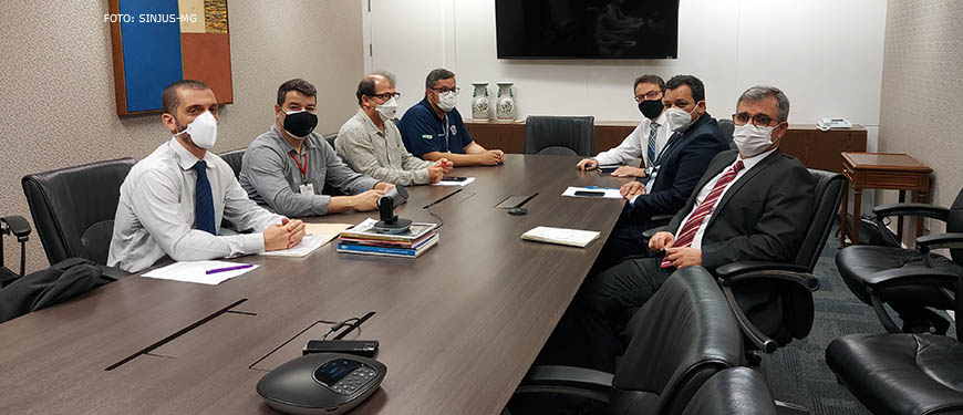 Sentados à mesa, de um lado, representantes do SINJUS, Serjusmig e Sindojus/MG, e, de outro lado, representantes do TJMG (sete homens brancos, de cabelos curtos, trajados socialmente usando máscaras respiratórias).