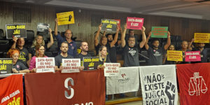 A imagem mostra um grupo de servidoras e servidores mobilizados em plenário, segurando cartazes com frases como “DATA-BASE JÁ!”, “DATA-BASE É LEI!” e “DATA-BASE EU NÃO ABRO MÃO!”. À frente, está estendida uma faixa do SINJUS-MG – Sindicato dos Servidores da Justiça de 2ª Instância do Estado de Minas Gerais, além de bandeiras de entidades sindicais. No topo da imagem, aparece a editoria “MOMENTO DECISIVO” e, em destaque, o texto: “Data-Base 2025 é aprovada em 1º turno e já volta à pauta às 10h desta 4ªf.”