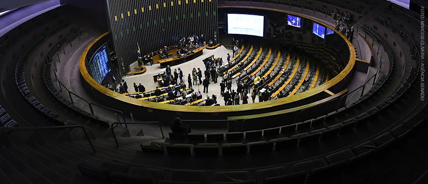 oto mostra o plenário da Câmara dos Deputados, vista do alto, com parlamentares em pé e sentados, durante uma sessão.