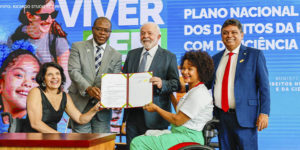 Presidente da República, Luiz Inácio Lula da Silva e Ministro dos Direitos Humanos e da Cidadania do Brasil, Silvio Almeida em cerimônia de lançamento do Novo Viver Sem Limite, no Palácio do Planalto. Eles estão cumprimentando pessoas com deficiência e exibem documento assinado na ocasião.
