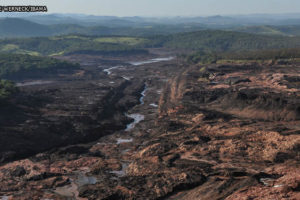 Imagem acessível: Paisagem com verdes montanhas ao fundo, no primeiro plano está parte da cidade de Brumadinho destruída pela lama com rejeitos tóxicos, proveniente do rompimento da barragem em 2019.