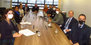 Foto de uma mesa de reunião retangular onde estão sentados de lado a lado os membros que compõem o Grupo de Trabalho do Assédio Moral e Sexual no TJMG.