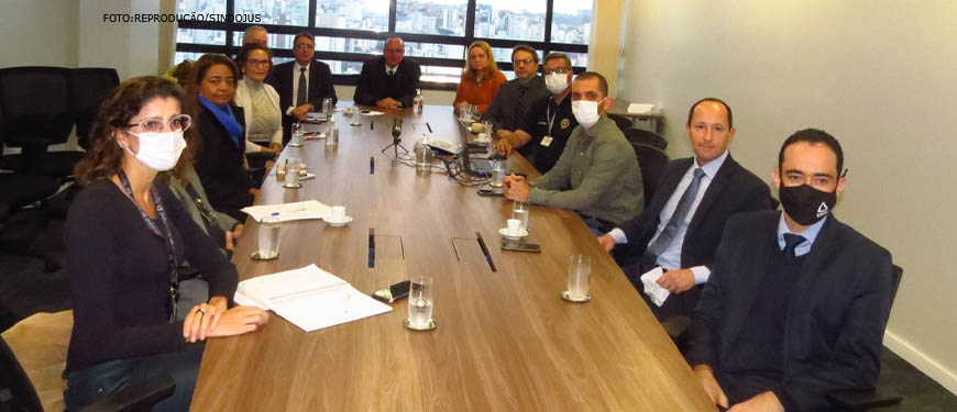 Foto de uma mesa de reunião retangular onde estão sentados de lado a lado os membros que compõem o Grupo de Trabalho do Assédio Moral e Sexual no TJMG.