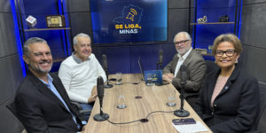 Imagem acessível: A imagem divulga o mais recente podcast do Se Liga, Minas. Na foto, mostra quatro pessoas em um estúdio, sentadas ao redor de uma mesa com microfones. Ao fundo, uma TV exibe o logotipo do podcast. O texto destaca: “Novo episódio do Se Liga, Minas traz debate sobre comunicação e o futuro do rádio”.