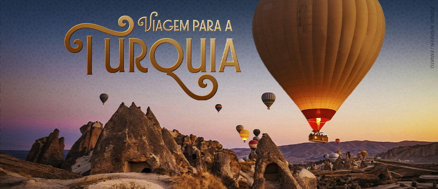 Imagem Acessível: Card de divulgação de viagem para a Turquia, com fundo azul e paisagem da Capadócia ao pôr do sol, marcada por formações rochosas e vários balões coloridos no céu. Em destaque, o texto diz: “Viagem para a Turquia” e “Viva momentos inesquecíveis entre o Oriente e o Ocidente”. A viagem será de 18 a 28 de outubro de 2026, com roteiro por Istambul, Capadócia, Pamukkale, Izmir e Bursa. A peça informa que as vagas são limitadas e que as inscrições devem ser feitas pelo formulário.