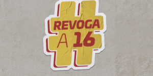 Montagem digital de um adesivo com a mensagem #REVOGAA16 sobre uma parede, o adesivo é tem cor de fundo amarelo com o texto em vermelho.