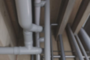A imagem mostra um conjunto de tubulações instaladas no teto de um ambiente interno, retratando uma área técnica do edifício Banlavoura (Afonso Pena, 1500). O destaque é para a ação do TJMG, que realizou reparos no sistema após denúncias do SINJUS sobre mau cheiro no local.
