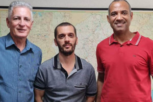 Há 3 homens lado a lado. Do lado esquerdo está um homem branco de cabelos brancos, trajando camisa azul e calça cinza (Deputado Federal Rogério Correia), ao centro está um homem branco de cabelos castanhos bem curtos, ele usa uma camisa cinza e uma calça jeans (Alexandre Pires, Coordenador - geral do SINJUS); à direita está um homem negro, de cabelos grisalhos bem curtos, ele usa uma camisa vermelha e uma calça jeans preta (Wagner Ferreira - diretor de assuntos Jurídico do SINJUS e vereador de Belo Horizonte).