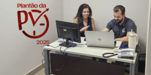A imagem mostra uma mulher de cabelos castanhos compridos e um homem branco, de barba e cabelos castanhos, vestindo camisa cinza do SINJUS, sentados lado a lado em uma mesa de atendimento, analisando informações em um notebook. O homem que faz o atendimento é o coordenador-geral do Sindicato, Felipe Rodrigues. Sobre a fotografia, aparece o símbolo vermelho do Plantão da PV 2025, com uma seta ascendente integrada a um relógio.