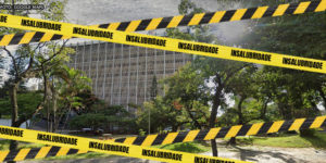 Foto diurna da fachada do edifício do TJMG situado à Praça Milton Campos. Sobre a foto,foram aplicadas faixas, em amarelo e preto, com a palavra "insalubridade", indicando o estado do local.