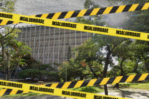 Foto diurna da fachada do edifício do TJMG situado à Praça Milton Campos. Sobre a foto,foram aplicadas faixas, em amarelo e preto, com a palavra "insalubridade", indicando o estado do local.