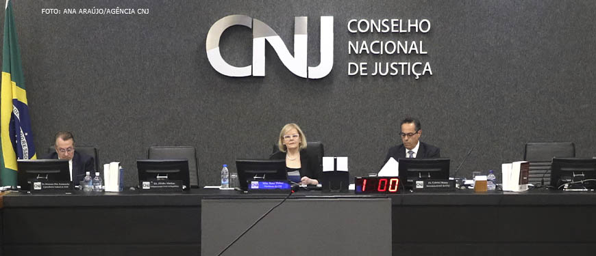 Imagem Acessível: Ministra Rosa Weber em reunião com conselheiros do Conselho Nacional da Justiça, em destaque está o letreiro inox do CNJ.