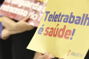 Em perspectiva estão servidores portando diversos cartazes, contendo palavras de ordem em protesto a favor do Teletrabalho no TJMG.