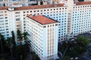 Vista aérea da Santa Casa de Misericórdia de Belo Horizonte, o prédio tem diversos blocos e muitos andares, a construção tem a pintura na cor azul com detalhes em branco. O telhado é em cerâmica.