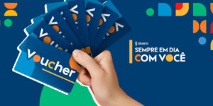 A imagem mostra no centro da uma mão segurando vários cartões azuis com a palavra “voucher” escrita em branco e laranja. Abaixo, em destaque, o texto “Confira os ganhadores do sorteio do Mês do Servidor”. O design transmite dinamismo e celebração. O slogan “Sempre em dia com você” se encontra no topo, sobre fundo azul com formas geométricas coloridas nas cores verde, laranja, vermelho e amarelo. --