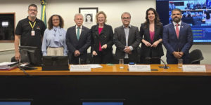 Na mesa principal de uma audiência no Congresso Nacional, está o coordenador-geral da Fenajud, junto de parlamentares e outros participantes do debate.
