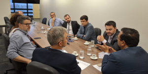 Imagem Acessível: A imagem mostra uma reunião formal entre representantes do SINJUS-MG e do TJMG, realizada em uma sala de reuniões com mesa retangular. O texto em destaque informa: “SINJUS conquista reajuste substancial do Auxílio-Saúde”, simbolizando uma vitória importante para os servidores do Judiciário mineiro, resultado da atuação sindical constante e articulada junto ao Tribunal. No inferior da imagem, é visível o logotipo do SINJUS-MG.