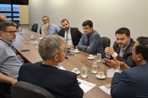Imagem Acessível: A imagem mostra uma reunião formal entre representantes do SINJUS-MG e do TJMG, realizada em uma sala de reuniões com mesa retangular. O texto em destaque informa: “SINJUS conquista reajuste substancial do Auxílio-Saúde”, simbolizando uma vitória importante para os servidores do Judiciário mineiro, resultado da atuação sindical constante e articulada junto ao Tribunal. No inferior da imagem, é visível o logotipo do SINJUS-MG.