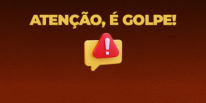 A imagem mostra o texto em destaque: “Atenção, é golpe!” com fundo vermelho escuro. Ao lado, há um ícone amarelo com um triângulo vermelho e um ponto de exclamação branco no centro, simbolizando alerta.