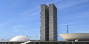 Imagem Acessível: A imagem mostra ao fundo o céu azul e a arquitetura icônica do Congresso, com as torres e cúpulas brancas. Em destaque, o texto: “Alerta: Câmara retoma debate sobre Reforma Administrativa e PEC 66 nesta 6ªf.”. A imagem sinaliza urgência para os servidores públicos.