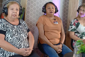 Há 3 mulheres sentadas no estúdio do SINJUS-MG, Maria Abadia de Souza (diretora de Finanças do Sisipsemg) , Antonieta Dorledo, presidente do Sindicato dos Servidores do Instituto de Previdência do Estado de Minas Gerais (Sisipsemg) e secretária da Mulher da Central dos Sindicatos Brasileiros (CSB) e Cristiane Sampaio, diretora Administrativa do SINJUS e coordenadora do Núcleo das Mulheres (NM).