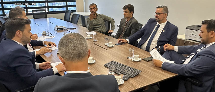 Representantes da presidência do TJMG em mesa de negociação com representantes sindicais do SINJUS-MG, Serjusmig e Sindojus/MG. Em destaque, falando aos presentes, está Alexandre Pires (coordenador-geral do SINJUS), ele apresenta uma expressão facial muito séria e gesticula apontando para um dos representantes do TJMG.