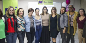 Integrantes do Núcleo das Mulheres posam abraçadas uma do lado da outra juntamente com as coordenadoras do NM Adriana Teodoro e Janaína Barbosa.