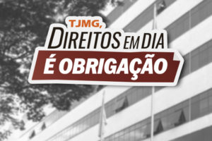 A imagem exibe a fachada do prédio do Tribunal de Justiça de Minas Gerais (TJMG), com destaque para a entrada principal, o nome da instituição em letras metálicas e bandeiras hasteadas ao fundo. Em primeiro plano, há um selo com a frase “TJMG, direitos em dia é obrigação”, representando o mote da campanha.