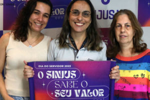 Fotografia contendo filiados do Sinjus segurando a placa com a logo tema do mês do servidor que se lê, "O Sinjus sabe seu valor".