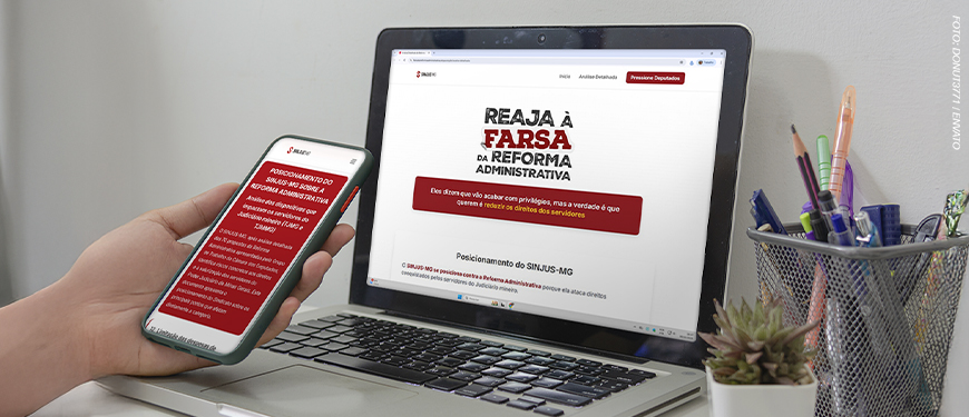 A imagem possui o fundo em tons de cinza mostrando uma pessoa segurando um celular diante de um notebook. Ambos exibem o hotsite do SINJUS sobre a Reforma Administrativa, com o título “Reaja à Farsa da Reforma Administrativa”.